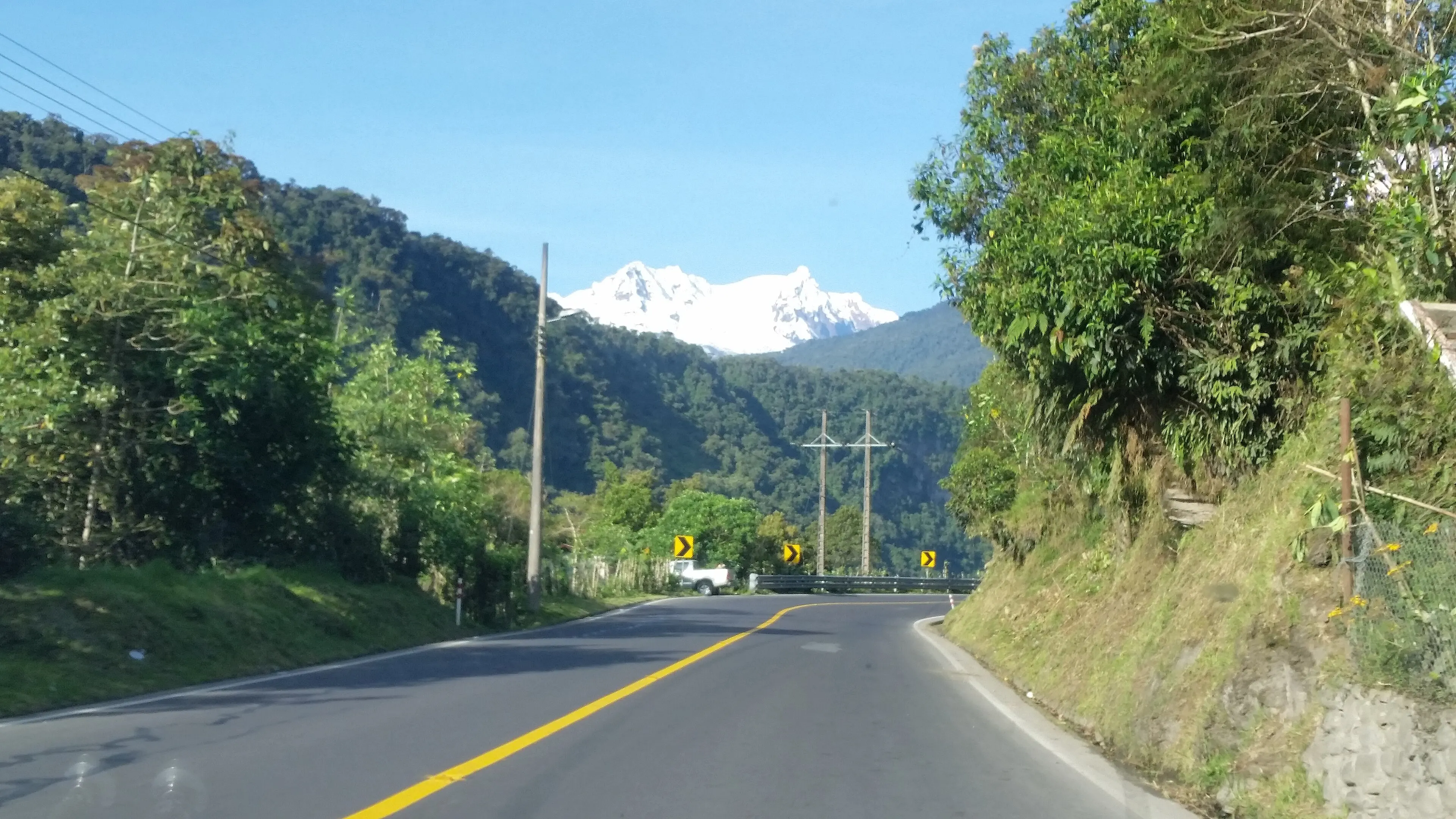 The E20 road between Cuyuja and Baeza winding through cloud forest under a snow-capped volcano